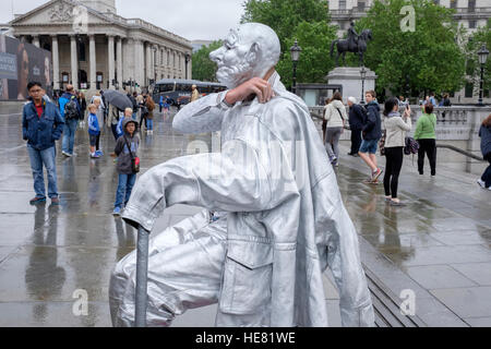 Eine Straße Künstler bedeckt in Silberfarbe setzt seine Jacke am Londoner Trafalgar Square Stockfoto