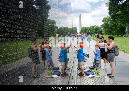 Schulkinder mit Hilfe ihres Lehrers machen Bleistift Abreibungen der Namen an der Wand des Vietnam Veterans Memorial. Stockfoto