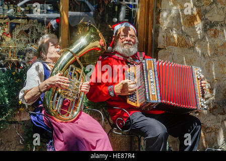 Santa Claus und seine Assistentin spielen Musikinstrumente während Straßenmusik zu Weihnachten in Hahndorf, SA, Australien. Stockfoto