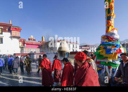 Lhasa: Tibeter umrunden die Barkhor (Pilgerweg) ein Darchen (Flagpost) vor dem Jokhang-Tempel, Tibet, China Stockfoto