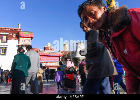 Lhasa: Tibeter umrunden die Barkhor (Pilgerweg) ein Darchen (Flagpost) vor dem Jokhang-Tempel, Tibet, China Stockfoto