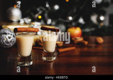 Traditionellen Eierlikör mit Zimt auf Holztisch mit Weihnachtsgeschenken Stockfoto