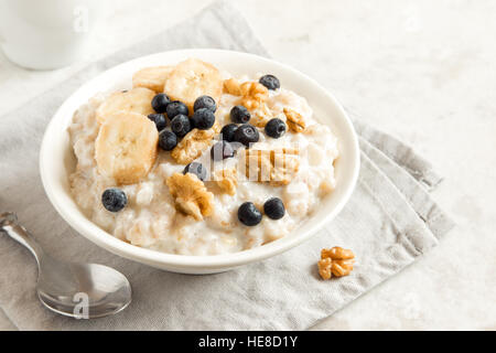 Haferflocken-Porridge mit Walnüssen, Blaubeeren und Bananen in Schale - gesunde Rustikales Frühstück Stockfoto