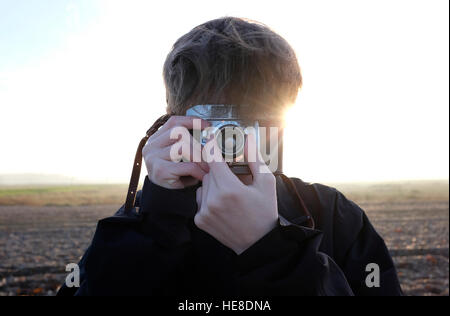 junge Männer stehen am Strand mit Retro-Kamera Stockfoto