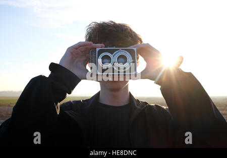 junge Männer stehen am Strand mit Retro-Kamera Stockfoto