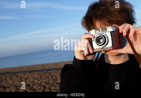 junge Männer stehen am Strand mit Retro-Kamera Stockfoto