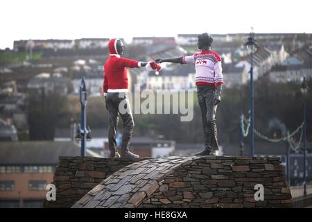 Friedensstatue „Hands Across the Divide“ in Londonderry, Nordirland, geschmückt mit Weihnachtspulern. Stockfoto