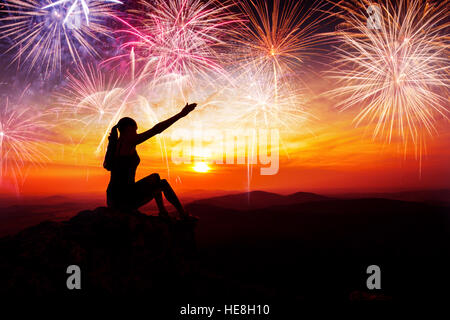 Silhouette der Frau sitzen, zeigen und beobachten das Feuerwerk. Konzept des neuen Jahres und Feier Stockfoto