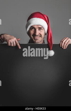 Glücklich lächelnden Mann in Nikolausmütze mit schwarzen leere Banner mit Textfreiraum Stockfoto