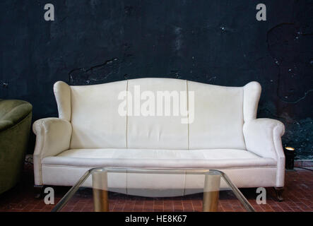 Altes Sofa auf schwarze Wand mit Textfreiraum Stockfoto