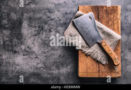 Metzger. Vintage Metzger Fleischerbeile mit Tuch Handtuch auf dunklen Beton oder Holz Küche Board. Stockfoto