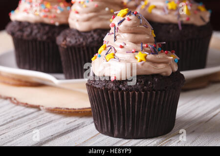 Leckere Schokolade Muffins mit Creme und Süßigkeiten Streusel auf den Tisch-Makro. horizontale Stockfoto