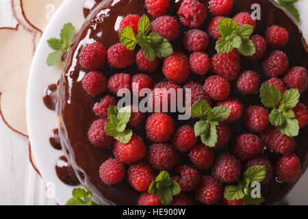 Schokoladen-Himbeer-Kuchen mit frischen Beeren hautnah auf einem weißen Teller. horizontale Ansicht von oben Stockfoto