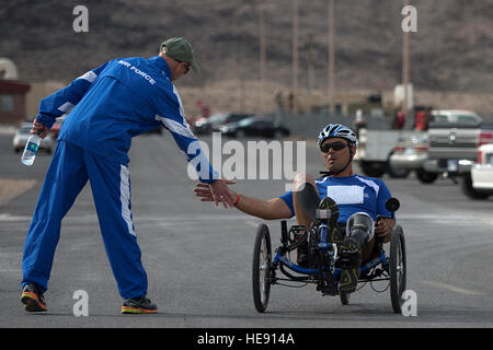 Christopher Aguilera Zyklen von Mike Sanders um ein High-Five zu erhalten, nachdem er das Rennen 9. April 2014, während der Air Force Versuche am Nellis Air Force Base, Nevada Aguilera, eine Luftwaffe verwundete Krieger beendete, platziert zuerst in seiner Kategorie während dem Radfahren Abschluss. Senior Airman Jette Carr) Stockfoto