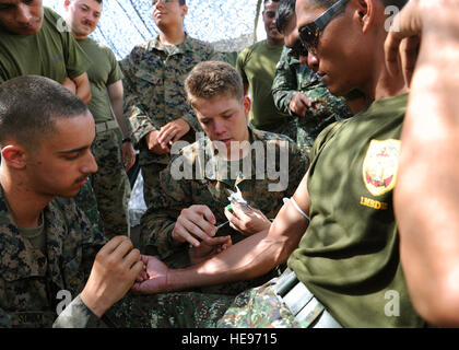 Von links nach rechts: U.S. Marine Lance Cpl. Andrew Sorrick, Kleinwaffen-Reparatur-Techniker und Mühle Stadt, Heimat, mit 3. Verordnung Wartungsfirma, Bekämpfung Logistik-Regiment 35, 3. Marineabteilung, III. Marine Expeditionary Force, US Navy Austin Byers, Gilbert, Arizona, Native, beobachtet und Corpsman Bekämpfung Leben Sparer Kursleiter mit der 3. medizinischen Bataillon, Bekämpfung Logistik Regiment 35, 3rd Marine Logistics Group , III. Marine Expeditionary Force, zeigen eine intravenöse Injektion auf philippinische Marine Private 1st Class Rixson Romo, ein Zamboanga City Native und Fahrer mit der Marine Trans Stockfoto