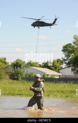 SPC. Michael Jung, der 817th Ingenieur-Gesellschaft, watet durch Hochwasser nach dem Laden eines eine Tonne schweren Sandsack aus einem Tieflader auf einem UH-60 Black Hawk-Hubschrauber 24 Juni, in der Nähe von einer Flut Deich auf 13th Street und Eisenbahn Avenue, Minot, N.D. North Dakota Army National Guard Soldaten reagieren auf eine dringende Bitte um Unterstützung aus der Stadt Minot in einer Bemühung, Wohnhäuser aus steigenden Flutwasser vom Fluss Souris zu speichern. Der Hubschrauber etwa 28 von den Sandsäcken auf gestellt der Problembereich entlang einer Flut Deich ordentlich die Häuser. Mehrere Wohngebiete von Minot wurden inunda Stockfoto