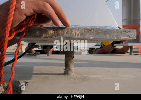 Staff Sgt Clyde Hunt führt sein Bein von einem Turm nach unten auf eine Schraube, die in einem Betonfundament eingebettet, während Staff Sgt Jonathan Arnold und Senior Airman Clinton Rowland ihre Beine im Hintergrund 26. August 2008, an einem geheimen Luftwaffenstützpunkt in Südwestasien führen. Alle drei Flieger sind das 379th Expeditionary Kommunikation Geschwader zugewiesen und sind Teil eines Teams, das Austausch von Alterung Türme mit stabiler Ersatz, der fast doppelt so lange dauern soll. Das Riesen-Voice-System wird verwendet, um wichtige Informationen zu allen base Bevölkerung sofort zu vermitteln. Sergeant Hunt, gebürtig aus Shreveport La. Stockfoto