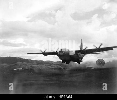 Ein Flugzeug der US Air Force C-130 Hercules geht niedrig über eine Drop-Zone im Süden Vietnams Bodentruppen im vorderen Bereich eine Palette an Zubehör anzubieten.  Tiefflug-Fallschirm-Extraktion-System (LAPES) ist erfolgreich im Einsatz, nach vorne gerichteten Bereich Websites zu versorgen, es unmöglich für ein Flugzeug ist zu landen. Stockfoto