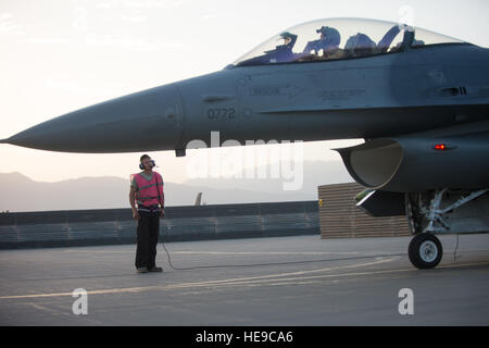 Ein US-Air Force f-16 Fighting Falcon "Triple Nickel" Flugzeug Pilot 555. Expeditionary Kämpfer-Geschwader von Aviano Air Base, Italien zugewiesen, wartet als Flieger aus dem 455. Expeditionary Aircraft Maintenance Squadron eine Endkontrolle der Flugzeuge Waffen vor dem Start auf einen Kampf gegen Ausfall von Bagram Air Field, Afghanistan, 14. Juli 2015 abzuschließen. Die f-16 ist ein multi-Role Kampfflugzeug, das ist sehr wendig und hat sich bewährt im Luft-Luft- und Luft-Boden-Kampf. Mitglieder der Triple Nickel werden zur Unterstützung der Operation Freedom Sentinel und NATO entschlossene S eingesetzt. Stockfoto