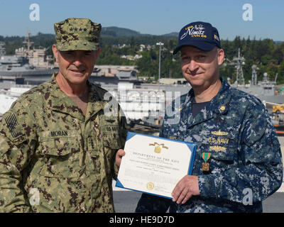 NAVAL BASE KITSAP-BREMERTON, Washington (25. Juli 2016) – Lt. CMdR Evan J. LaFrance erhält ein Navy/Marine Corps Achievement Medal von Admiral Bill Moran, Vice Chief of Naval Operations, auf dem Flugdeck der USS Nimitz (CVN-68) für die Reaktion auf einen elektrischen Schlag Opfer auf dem Pier. LaFrance geleitet und verwaltet Personal- und erste Hilfe in der Szene wenn restlich auf Szene, Verkehr und Massenkontrolle zu lenken. Nimitz wird derzeit eine geplante inkrementelle Wartungsarbeiten Verfügbarkeit im Puget Sound Naval Shipyard und Intermediate Maintenance Facility, wo das Schiff s empfängt Stockfoto