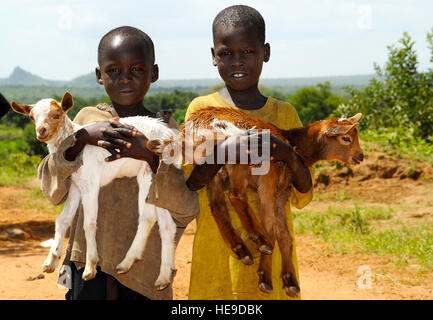 Zwei lokale Dorf jungen bringen ihr Baby Ziegen während eines tierärztlichen bürgerschaftliches Engagement-Projektes am 5. Juni in Kagamongole, Uganda geimpft werden. US Armee-Service-Mitglieder zugewiesen, kombiniert Joint Task Force-Horn von Afrika, behandelt 402nd Civil Affairs Bataillon Spezialität Funktionsteam zusammen mit ugandischen Tierarzt Studenten an der Makerere University und 31 CAHW mehr als 30.000 Tiere während sechs Tagen nach der Behandlung in der Karomoja Region. Die Zusammenarbeit von ugandischen Tierarzt Studenten, Servicemembers CJTF-HOA und verschiedenen nichtstaatlichen Tierarzt Agenturen während der VETCAP zur Folge Stockfoto