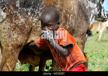 Eine junge Dorfjunge nutzt die Möglichkeiten der Milch ihm während Service-Mitglieder zugewiesen, kombiniert Joint Task Force-Horn von Afrika, 402nd Civil Affairs Bataillon Spezialität Funktionsteam in Zusammenarbeit mit den ugandischen Tier medizinisches Personal behandelt mehr als 30.000 Tiere bei einem tierärztlichen bürgerschaftliches Engagement Projekt 10 Juni in das ländliche Dorf Nabilatuk, Uganda. Stockfoto