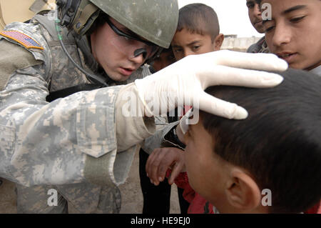 US Army Spc. Marcel Roth, Sanitäter aus C Company, 225. Brigade Support Battalion, befestigt 66. Engineer Company, 2nd Stryker Brigade Combat Team, 25. Infanterie-Division, behandelt einen irakischen Jungen in der Meshahadah Provinz, Irak, am 27. Januar. Stockfoto