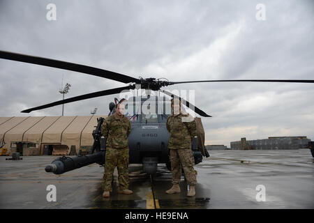 US Air Force Staff Sgt. Jean Vega Martinez, 83. Expeditionary Rescue Squadron Flugingenieur und sein Vater US Air Force Senior Master Sergeant Carmelo Vega Martinez, 438th Air Expeditionary Wing/NATO Air Training Command-Afghanistan-recruiting-Berater, posieren vor einem HH-60 Pave Hawk-Hubschrauber vor Staff Sgt Vega Martinez "Neueintragung Zeremonie, 17. März 2014, Bagram Air Field, Afghanistan. Vor der Zeremonie, Vater und Sohn hatte beide Ponce, Puerto Rico Eingeborenen, einander in zwei Jahren aufgrund der militärischen Verpflichtungen nicht gesehen.  Die beiden sind in separaten Operation Enduring befreit bereitgestellt. Stockfoto