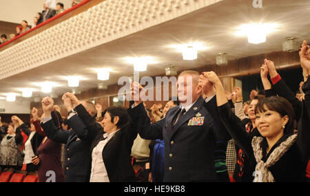 Zuschauer und Transit Center am Manas Command Chief Master Sgt. Jim Dowell erheben ihre Hände in der Einheit zum hundertjährigen Jahrestag der Weltfrauentag Day Konzert in der kirgisischen Nationalphilharmonie, 25 Februar, in Bischkek, Kirgisistan. Zu Ehren des Internationalen Frauentags veranstaltete Kongress Frauen der Kirgisischen Republik 25 US Air Force Service-Mitglieder aus dem Transit am Manas. Senior Airman Nichelle Anderson) Stockfoto