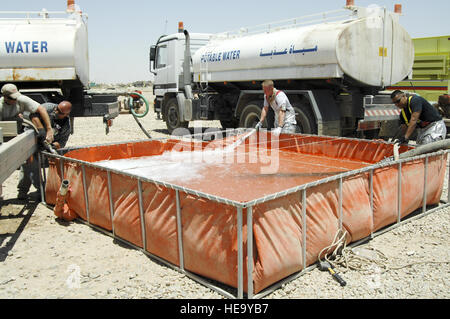 Feuerwehrleute aus dem 407th Expeditionary Civil Engineer Squadron (ECES) und zivile Auftragnehmer füllen Sie einen Wassertank Wasser LKW Löschangriff bei der US-Armee-Fuhrpark "Road House", Camp Adder, Irak, 19.Juni Feuer zu liefern. Aufgrund von Munition in das Gebäude und kein Potenzial für den Verlust des Lebens enthalten die Feuerwehrleute wechselte zu defensiven Operationen für die Blaze mit sechs LKWs unter Kontrolle zu halten und beschränkt sich auf das Gebäude. Stockfoto