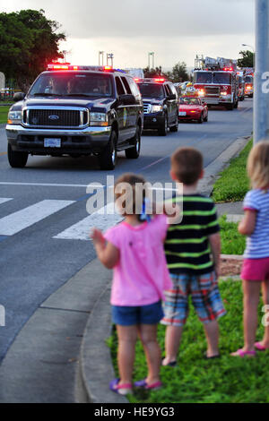 Kinder beobachten während der Woche Feuer zur Prävention gegen Parade auf Kadena Air Base, Japan, 9. Oktober 2013 als Mitglieder aus der 18. Civil Engineer Squadron Fahrt entlang einer Straße. Die Kadena Feuerwehr führte die Parade durch Gehäuse mit Sockel beim werfen Süßigkeiten an Massen von Kinder und Mitglieder des Team Kadena als Teil einer einwöchigen Bemühung, Brandschutz und Prävention zu fördern.  Staff Sgt Amber E. N. Jacobs) Stockfoto