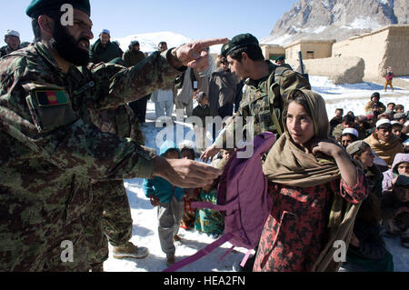 Afghan National Army Soldaten verteilen Rucksäcke mit Schulmaterial für Kinder im Dorf Tandan, Afghanistan, Jan. 25. 203. ANA Corps religiöser und kultureller Berater Team ausgehändigt Lieferungen während ein Outreach-Mission unter der Leitung von der afghanischen Regierung und Sicherheitskräfte mit Sitz in Paktya Provinz.  US Air Force Personal Sgt. Barry Loo, Paktya Provincial Wiederaufbau Team Public Affairs) Stockfoto