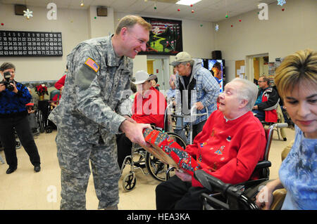 Oberst Brian Trenda, North Dakota Joint Force Hauptquartier Direktor des Armee-Personals, gibt ein Weihnachtsgeschenk, ein Bewohner von North Dakota Veteranen Haus in Lissabon, N.D., Dez. 15, während der jährlichen North Dakota National Guard geförderte Weihnachten party Zuhause Veteranen. North Dakota Air und Army National Guard Mitglieder Spenden persönliche Geld für Geschenke und präsentieren ihnen den Veteranen im Pflegeheim jedes Jahr während der Ferienzeit. Stockfoto