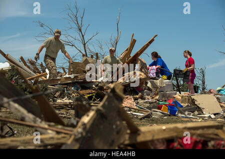 Kapitän Van Blaylock (von links nach rechts) und Senior Airman Joshua Jacobs helfen Einwohner Alyson Tinney und Elise Hopkins durch die Trümmer, die auf der Suche nach wiederverwertbare Gegenstände 22. Mai 2013, in Moore, Oklahoma suchen Ein Tornado EF-5 reiste mit Winde erreichen mindestens 200 km/h, 20 Meilen, eine zwei-Meile-breite Schneise der Verwüstung, Nivellierung Häuser, Fahrzeuge zerkleinern und tötet mehr als 20 Personen 20 Mai verlassen. Mehr als 115 Oklahoma Nationalgarde Mitglieder wurden aktiviert, um die Rettungs- und Hilfskräfte Bemühungen zu unterstützen. Jacobs ist eine gemeinsame terminal Angriff Controller zugewiesen, 146. Air Support Operations S Stockfoto