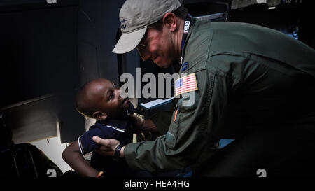 Capt Lindsey Kinsinger hilft, ein Kind ins Cockpit einer C-130J Super Hercules auf der Africa Aerospace & Defence Expo Waterkloof Air Force Base, South Africa, 20. September 2014.  Der c-130 aus die 37th Airlift Squadron war Teil eines Gesamt-Force-Teams von Guard, Reserve und Aktivaufgabe Soldaten und Piloten auf der Expo. Air Show Teilnehmer erhielten die Möglichkeit, das Innere eines Luftwaffe C-130J und c-17 Globemaster III zu sehen. Staff Sgt Travis Edwards) Stockfoto