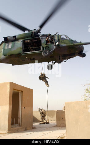 US Air Force (USAF) Pararescuemen zugewiesen, 101. Expeditionary Rescue Squadron (ERQS), Abstoßen von einem schwebenden USAF HH - 60G Pave Hawk-Hubschrauber, Such- und Rettungsmissionen (SAR) Training am Flughafen Bagdad, Irak, während der Operation IRAQI FREEDOM durchgeführt. Stockfoto