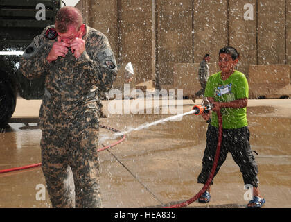 JOINT BASE BALAD, der Irak--ein irakischen Jungen tränkt Armee Sgt. Joshua McGinnis, 23. Ordnance Company Feuerwehrmann, tagsüber irakische Kinder hier 10. Oktober 2009. Sergeant McGinnis wird hier aus Grafenwöhr, Deutschland, bereitgestellt und stammt aus Springfield, Missouri Staff Sgt Heather M. Norris) (veröffentlicht) Stockfoto