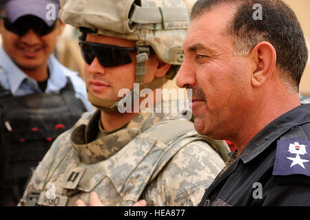 Irakische Polizei Kommandeur Lt. Col Ghazi Hamed Goma'a spricht zu US Army Captain Jeffrey Vargo aus der 25. spezielle Truppen Bataillon Sicherheitsabteilung und 25. Infanterie-Division am Ende der Waffen Einarbeitung, Schulung, gelehrt, irakische Polizisten aus Tikrits Al Sequor Polizeistation von US-Soldaten aus der Distanz auf das Feuern Palette von Kontingenz operative Basis Speicher , im Nordirak, 15 Juli. Stockfoto