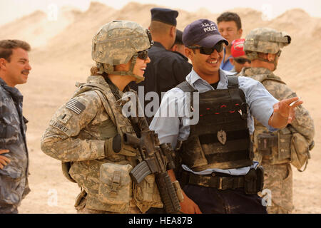 US Army 1st Lt. Julie Leggett, Executive Officer für die 25. spezielle Truppen Bataillon Sicherheitsabteilung, 25. Infanterie-Division, Gespräche mit einem irakischen Polizisten während Waffen Einarbeitung Ausbildung, von US-Soldaten aus der Distanz auf das Feuern Palette von Kontingenz operative Basis Speicher, im Nordirak, 15 Juli unterrichtet. Stockfoto
