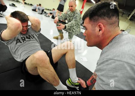 Fallschirm Infanterist Pvt. Steven Black, eine Firma 1st Battalion (Airborne) 501. Infanterie-Regiments, gebürtig aus Coaling, Calif., kämpft, um ein paar weitere Situps in den abnehmenden Sekunden den Situp Teil der Experte Infanterist-Abzeichen Armee körperliche Fitness-Test kurz nach 4 Uhr früh morgens auf gemeinsamer Basis Elmendorf-Richardson, Alaska, 22. April 2013, Spc. Brian McLaughlin zwar Abpumpen , A Firma 1st Battalion (Airborne) 501. Infanterie-Regiments, gebürtig aus Meadville, Penn, hält seine Füße und 1st Sgt. Erick Ochs, Headquarters und Headquarters Company zugewiesen, 1. Bat Stockfoto