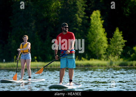 Paddeln Sie Trevor Bird, Paddle Board Instructor bei der Otter Lake Lodge und Senior Airman Sheriah Colcleaser, mit 673rd Medical Group, in Richtung Zentrum von Otter Lake auf gemeinsamer Basis Elmendorf-Richardson, Alaska, Juni 22. Die Lehrer lehrt richtiges grundlegende Paddle Board Kontrolle wie sie Otter Lake Runde Hindernisse im seichten Wasser zu vermeiden. Flieger Christopher R. Morales) Stockfoto