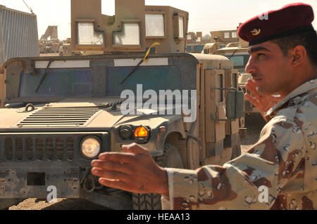 CAMP TAJI, Irak - Hakem, eine irakische Armee privat, leitet USA und IA Soldaten wie sie Laufwerk M1114 HMMWVs von Taji Umverteilung Eigenschaft Hilfe Team HMMWV hier vor kurzem zum nächsten staging Punkt auf den irakischen Teil des Lagers Hof. Die RPAT arbeitet mit Multi-National Security Transition Command – Irak bis gepanzerten HMMWVs umdrehen, die an die irakische Regierung für den Einsatz von IA und irakische Polizei verkauft wird. Staff Sergeant Dilia Ayala) Stockfoto