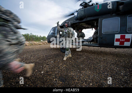 US-Armee HH - 60L Black Hawk Hubschrauber Flugingenieur signalisiert tierärztliche Wurf Träger Ansatz als US Armee SGT Leslie Langford, Eckzahn Handler, 550. militärischer Arbeitshund Ablösung, Fort Bragg, N.C., seinen Hund Ted, einen simulierten Eckzahn Unfall am Joint Readiness Training Center (JRTC), Fort Polk, Louisiana, 23. Februar 2013 tröstet. Service-Mitglieder am JRTC 13 / 04 sind in Bekämpfung Patientenversorgung und aeromedical Evakuierung in einer simulierten Kampf Umgebung ausgebildet.  Techn. Sgt John R. Nimmo, Sr. /) DIGITAL Stockfoto