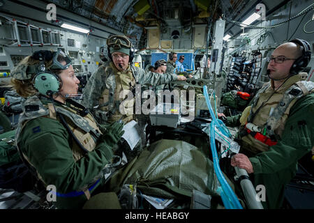 Von links, US Air Force Captain Danielle Cooper, Krankenschwester Flug Krankenschwester, 43. Aeromedical Evakuierung-Geschwader, Papst Army Airfield, N.C., Gespräche mit Intensivmedizin Transport Teammitglieder US Air Force Lieutenant Colonel Alan Guhlke, Anästhesist und Kapitän Daniel Bevington, Intensivpflege Krankenschwester, beide mit 711th menschliche Leistung Flügel, Wright-Patterson Air Force Base, Ohio, an Bord einer c-17 Globemaster III am Joint Readiness Training Center (JRTC) , Fort Polk, Louisiana, 18. Januar 2014. Service-Mitglieder am JRTC 14-03 sind in Bekämpfung Patientenversorgung und aeromedical Evakuierung in einer simulierten Kampf Umgebung ausgebildet.  Mas Stockfoto