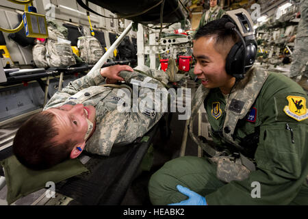 US Air Force Senior Airman Wilson Tsao flugmedizinischen Dienst Geselle, 18. Aeromedical Evakuierung-Geschwader, Kadena Air Base, Okinawa, Japan, kümmert sich um das Wohlergehen der Schauspielpatienten Staff Sgt. Logan Shilcox während während des Fluges an Bord einer c-17 Globemaster III im Joint Readiness Training Center, Alexandria, Louisiana, 13. März 2014. Service-Mitglieder am JRTC 14-05 sind in Bekämpfung Patientenversorgung und aeromedical Evakuierung in einer simulierten Kampf Umgebung ausgebildet. Shilcox ist ein Sanitätsdienst Geselle mit dem 81. Medical Group, MacDill Air Force Base, Miss...  Master Sergeant John R. Nimmo, Sr. /) Stockfoto