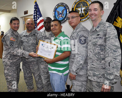 Lieutenant Colonel Alan McKewan, Kommandant der Joint Task Force-Bravo Armee Truppen Bataillon, präsentiert ein Anerkennungszertifikat Jose Adalberto Mejia für seine Taten helfen gerne bei der Szene von einem Fahrzeug Unfall, Soto Cano Air Base, Honduras, 16. Dezember 2013. Am Abend des 11. Dezember 2013, fuhr Adalberto Mejia ein Taxi mit US Air Force Captain Allen Bear, US Air Force Master Sgt. Michael Batres, US Army Staff Sgt John Fowler und US Armee Sgt. Willie Price (im Bild) als Passagiere bei die Männern erlebt ein Fahrzeug fällt auf, dass einer Kuh auf die Straße gewandert war. Das Fahrzeug Stockfoto