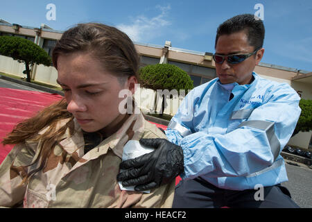 Kadena Notfall Responder behandelt US Air Force Airman Gabrielle Bully, 18. Operations Support Squadron Aircrew Flug Ausrüstung Lehrling und simulierte Schusswunden Wunde Opfer, während eine aktive Schütze Übung 4. Mai 2016, auf der Kadena Air Base, Japan. Simulierte Opfer wurden mit Moulage Make-up und zahlreiche lebensechte Wunden ausgestattet, um eine realistische Erfahrung für Einsatzkräfte zu gewährleisten.  Staff Sgt. Maeson L. Elleman) Stockfoto