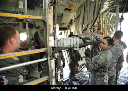 US Air Force Senior Airman Ashley Figueroa, rechts vorne mit der 81. Aerospace Medicine Squadron (AMDS) hilft anderen Mitglieder der 81. Medical Group als Oberstleutnant Mikelle Maddox, ein Arzt mit der 81. AMDS Rollenspiel als Patient an Bord einer c-130 Hercules-Flugzeuge während der Evakuierung der Luft training 14. März 2013, MacDill Air Force Base, Miss zu sichern. Das Training sollte Erfahrung in der Konfiguration von c-130 s für Patiententransport zu schaffen. Flieger mit dem 81. MDG, 81. AMDS, 81. medizinische Operations Squadron und 53. Wetter Reconnaissance Squadron beteiligte sich an der Stockfoto