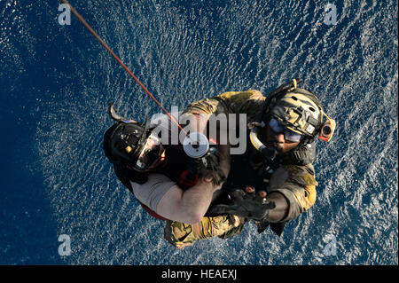 Ein Pararescueman, Recht, hilft Chief Master Sgt. Gerald Barnett, wie er in einem HH - 60 G Pave Hawk-Hubschrauber als Bestandteil einer Wasser-Rettungs-Übung 20. März 2014, in der Nähe von Camp Lemonier, Dschibuti gehisst wird. Die Ausbildung dazu beigetragen, die Flieger in Wasser Rettung Fähigkeiten beherrschen bleiben. Der Pararescueman zugeordnet ist, die zugewiesenen der 82. Expeditionary Rescue Squadron. Barnett ist eingetragene Berater mit 449th Air Expeditionary Group. Staff Sgt. Staci Miller) Stockfoto