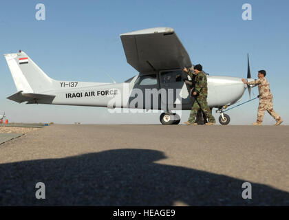 Betreuer mit der irakischen Luftwaffe 1. Wartung Geschwader Push eine Cessna 172 Skyhawk in einen Parkplatz nach dem Flugzeug aus einer Trainingsmission Kennzeichnung der 3000. Sortie durch die irakische Training Wing bei Kirkuk Regional Air Base, Irak, Dez. 18 zurück.  Der Flügel gelang das Kunststück mit Hilfe der 52d Expeditionary Flying Training Squadron. Der Ausfall wurde von Oberstleutnant Randall Bristol, 52d EFTS Fluglehrer und Lt. Saif, IqAF Flugschüler geflogen.  Oberst Bristol ist Geilenkirchen Air Base in Deutschland eingesetzt.  Senior Airman Randi Flaugh) Stockfoto